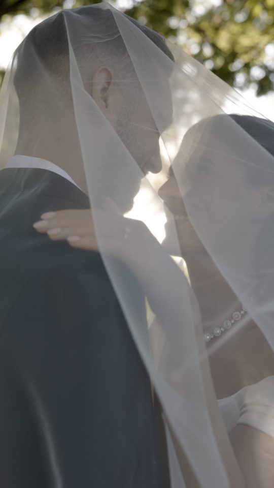 Romantic editorial portrait of a bride and groom beneath the veil