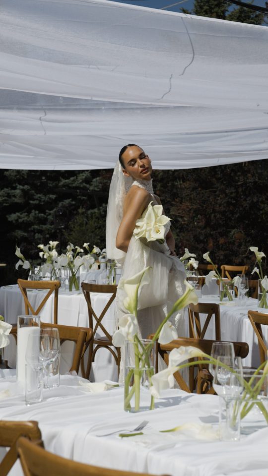 Bride posing with her bouquet surrounded by elegant wedding tables and floral arrangements