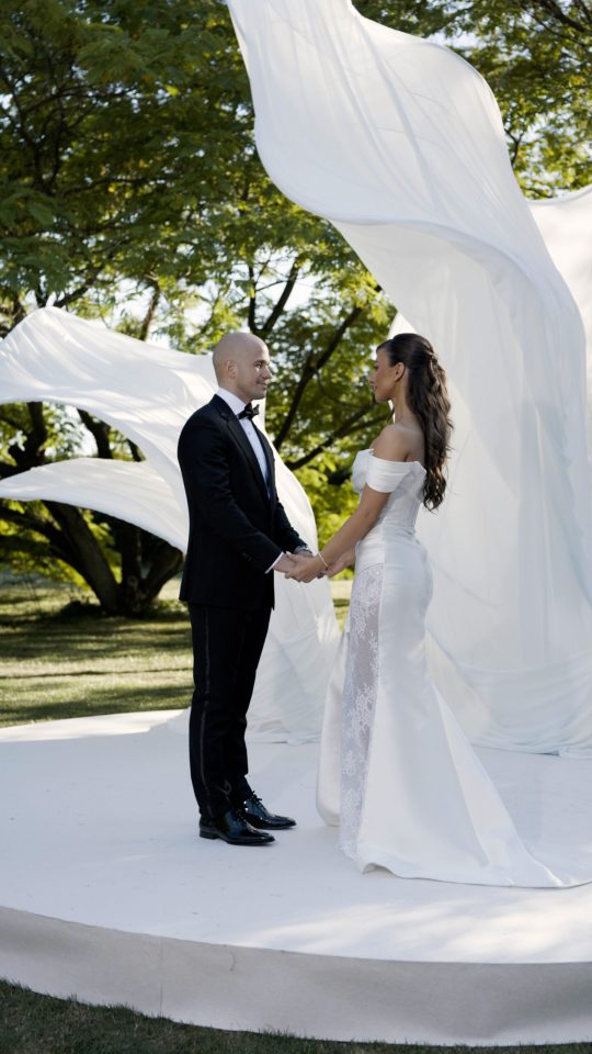 Bride and groom standing beneath a grand white wedding altar